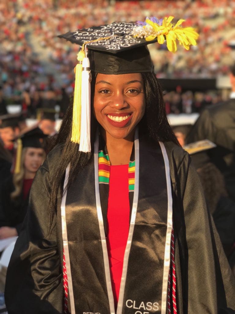 Mmeri scholar in cap, gown, and kente stole at her college graduation ceremony